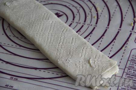 С помощью скалки слегка раскатать рулет в длину. Вилкой сделать неглубокие насечки (для того чтобы вилка не липла к тесту при нанесении насечек, можно зубья вилки немного обмакнуть в муку).