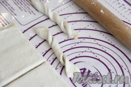 Накрыть начинку второй частью теста, а затем слегка раскатать тесто скалкой. Нарезать тесто на полоски шириной, примерно, 1,5 сантиметра. Перекрутить получившиеся полосочки пару раз, формируя жгутики, как на фото.