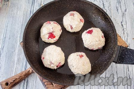 В сковороду влейте растительное масло и хорошо разогрейте. Из творожной массы сформируйте шарики, выложите их на сковороду, слегка приплюсните и жарьте под крышкой в течение 3-4 минут при слабом нагреве.