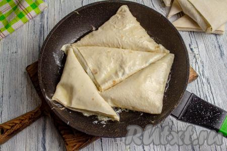 К этому времени на плите разогрейте сковороду с маслом. Выложите подготовленные треугольники. Обмакивать в смесь яйца и молока нужно столько заготовок из лаваша, сколько у вас одновременно поместятся на сковороде. Заранее обмакивать в молочно-яичную смесь заготовки не нужно.