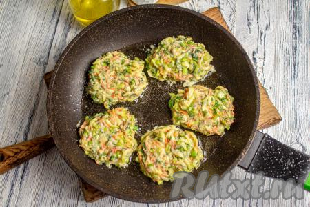 На раскалённую сковороду с растительным маслом, выкладывайте столовой ложкой кабачковую массу в виде оладушек. Жарьте при небольшом нагреве плиты под крышкой 3-4 минуты (до подрумянивая оладий снизу).&nbsp;