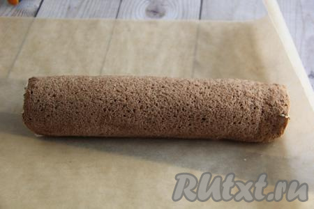 Завернуть бисквит с кремом, начиная со стороны с бананом, в рулет. Завернуть рулет в пергамент и убрать в холодильник на ночь.