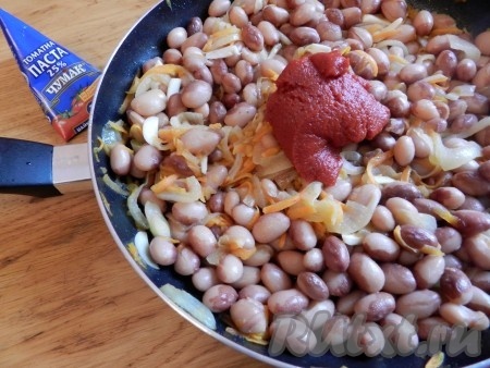 На растительном масле обжарить лук и морковь, добавить фасоль, затем чеснок и томатную пасту. Добавить соль и специи. Разбавить водой от варки фасоли и потушить минуты три все вместе.