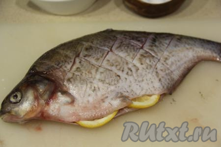 Счистить с леща чешую, затем из брюшка удалить внутренности, отрезать плавники и хвост, промыть рыбку под проточной водой и обсушить её бумажным полотенцем. На поверхности рыбы  острым ножом&nbsp;сделать надрезы крест-накрест. Лещ - рыбка достаточно костлявая. Надрезы необходимы, чтобы мелкие косточки успели хорошо пропечься в духовке. Натереть леща солью снаружи и внутри. Вложить в брюшко пару долек лимона.