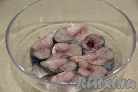 У скумбрии из брюшка удалить внутренности с чёрной плёночкой, отрезать голову, плавники и хвост, хорошо промыть. Нарезать скумбрию на кусочки и выложить поверх лука и лимона. Все кусочки скумбрии присыпать солью и сахаром.