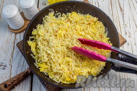 С запаренной лапши слейте лишнюю жидкость, а саму лапшу выложите в сковороду к яйцам и вместе прогрейте 1-2 минуты, помешивая.