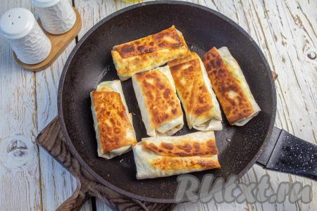 Затем переверните на другую сторону и обжаривайте с другой стороны в течение 1-2 минут (до румяности). Готовые рулетики из лаваша переложите на тарелку. Таким способом обжарьте все заготовки.&nbsp;