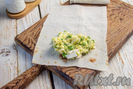 Зрительно разделите начинку на столько частей, сколько частей лаваша у вас получилось. На лист лаваша выложите одну часть начинки ближе к одному из краёв.&nbsp;