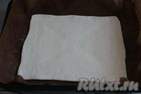 Застелить противень тефлоновым ковриком (или пергаментом). Тесто (у меня 2 пласта по 250 грамм) на припылённой мукой поверхности раскатать в два квадратных пласта размером, примерно, 28 сантиметров на 28 сантиметров. Выложить первый пласт на застеленный противень.