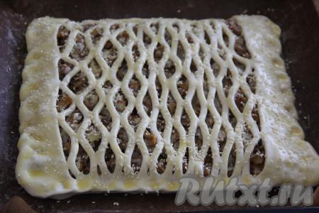 Поверх начинки выложить решётку из теста. Края теста подвернуть и запечатать начинку между двумя пластами теста. Смазать верх пирога взбитым желтком и, по желанию, посыпать кунжутом.