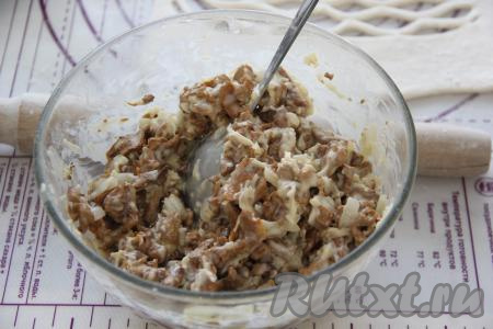 Переложить остывшие лисички со сковороды в тарелку, добавить к ним натёртый на крупной тёрке сыр, сырые яйца, сметану и 2 столовые ложки муки, перемешать грибную начинку.