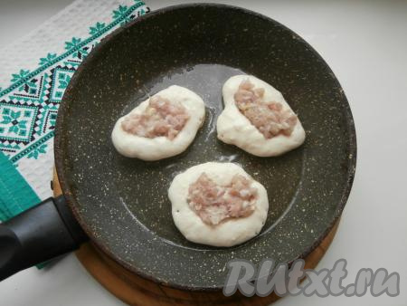 В сковороде хорошо прогреть растительное масло, затем выкладывать по 1 столовой ложке теста в виде оладий. В центр этих "оладий" выкладывать по 2 чайных ложки подготовленного фарша.