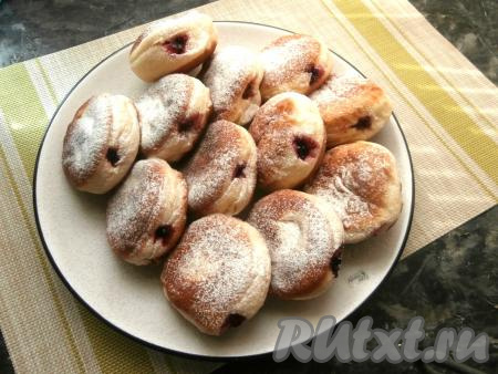 Далее сбоку в каждом пончике сделать дырочку (палочкой или трубочкой) и с помощью кондитерского мешка начинить пончики вареньем. Сверху посыпать сахарной пудрой.