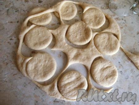 Далее тесто обмять, раскатать в лепёшку толщиной около 0,7 сантиметров. Стаканом вырезать кружочки - будущие пончики.