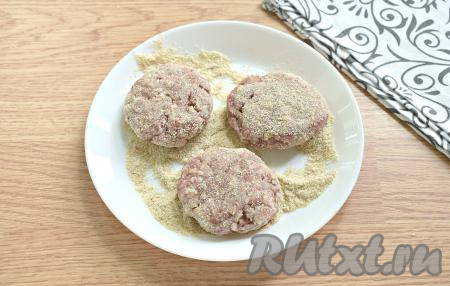 Обваливаем мясные колобки со всех сторон в панировочных сухарях и немного прижимаем их рукой, придавая таким образом форму круглых котлет.