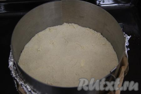 Перетереть массу руками в мелкую крошку. Половину крошки выложить в разъёмную форму для выпечки диаметром 22 сантиметра. В качестве формы я взяла разъёмное кольцо диаметром 22 сантиметра, а дно сформировала из фольги, сложенной в несколько слоёв, и пергамента, а затем выложила половину крошки. Утрамбовать крошку в форме руками. Поставить форму и оставшуюся крошку в холодильник на время, пока подготавливаем начинку.