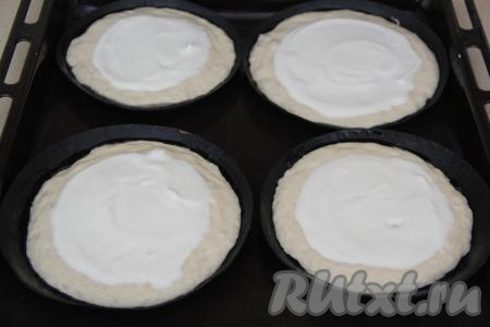 Формы для шанег смазать маслом и, не перемешивая тесто, разложить его по формам. Вместо специальных форм для шанег можно взять любые формы диаметром от 6 до 18 сантиметров с низкими бортиками.&nbsp;Я выпекала 5 шанег в формах диаметром 12 сантиметров и 6 штук в формах диаметром 6 сантиметров. В серединку каждой заготовки шаньги выложить сметанную начинку и аккуратно распределить по поверхности теста, немного не доходя до края.