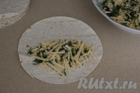 Из лаваша вырезать кружочки. Я вырезала кружочки диаметром 20 сантиметров, ориентируясь на диаметр сковороды, на которой планировала жарить кутабы (диаметр сковороды должен быть чуть больше диаметра круга из лаваша). Удобно вырезать круги, приложив сверху тарелку нужного диаметра. Всего я вырезала 8 кругов из лаваша (то есть в результате у меня получилось 8 кутабов). Визуально круг лаваша разделить на две части. На одну из частей круга выложить, примерно, 2 столовые ложки без верха смеси сыра и зелени. Выкладывая начинку, отступаем от края круга 1-2 сантиметра.