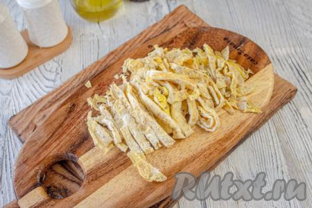 Обжаренные блины сложите вместе, разрежьте пополам, а затем нарежьте соломкой.