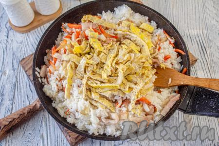 Когда овощи станут мягкими, в сковороду выложите отваренный рис, яичные блинчики, влейте соевый соус, аккуратно перемешайте, приправьте по вкусу солью и чёрным молотым перцем. Томите всё вместе на небольшом огне 2-3 минуты, иногда перемешивая.