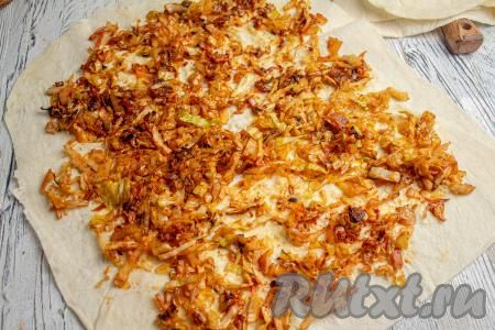 Расстелите лист лаваша, смажьте его поверхность яйцом. Распределите ровным слоем половину капустной начинки, отступая немного от краёв.&nbsp;