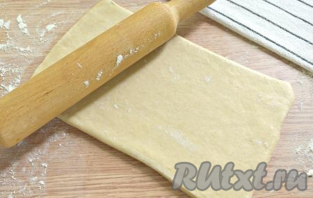 На присыпанный мукой стол выкладываем размороженный пласт слоёного теста. Раскатываем его слегка в одном направлении. У меня получился пласт размером 24 сантиметра на 14 сантиметров.