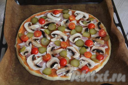 Затем разложить на пиццу шампиньоны, помидоры и огурчики.