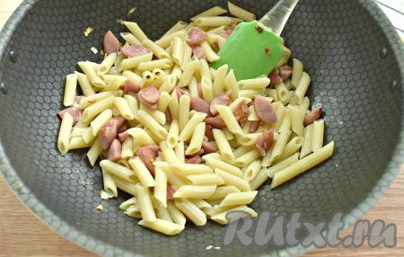 Перекладываем отварные макароны на сковороду к сосискам и луку, перемешиваем.