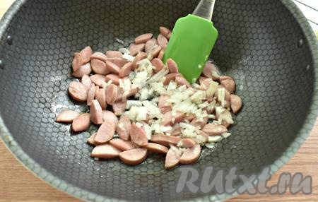 К обжаренным сосискам добавляем лук, перемешиваем и готовим, иногда помешивая, до мягкости лука (мне потребовалось 3 минуты).