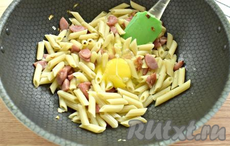 В сковороду с макаронами и сосисками разбиваем яйцо.