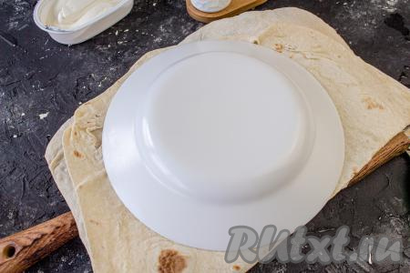 У меня было 2 листа лаваша. Первый лист лаваша сложите вдвое, сверху приложите перевёрнутую тарелку (у меня тарелка диаметром 20 сантиметров) и вырежьте круг. Аналогично вырежьте круги из второго листа лаваша.