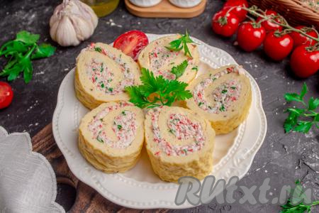 Перед подачей яичный рулет нарежьте на небольшие кусочки, разложите на плоской тарелке и подавайте к столу. Посмотрите, какими аппетитными получаются рулетики с начинкой из крабовых палочек и сыра. Уверена, вкус этой нежной закуски понравится многим!