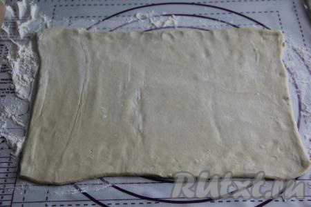 Слоёное тесто разморозить при комнатной температуре. Я разделила тесто на две части. Одну часть теста сделала побольше, она стала основой пирога. На присыпанной мукой поверхности большую часть слоёного теста слегка раскатать в пласт и переложить на противень, застеленный пергаментом.