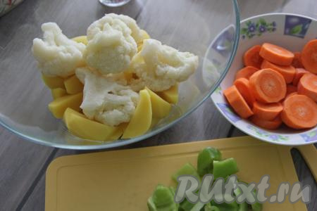 Подготовить продукты для приготовления филе индейки с овощами в духовке. Картошку почистить и нарезать на крупные дольки. Выложить в глубокую миску цветную капусту и картошку. Я использовала замороженную цветную капусту, уже разделанную на соцветья (предварительно не размораживала). Если вы готовите со свежей цветной капустой, то разделите её на соцветия, промойте, отваривать её предварительно не нужно. Морковь почистить и нарезать на кружочки. Болгарский перец, очищенный от семян, нарезать на крупные кусочки. В миску с картошкой и цветной капустой выложить нарезанные морковь и болгарский перец.