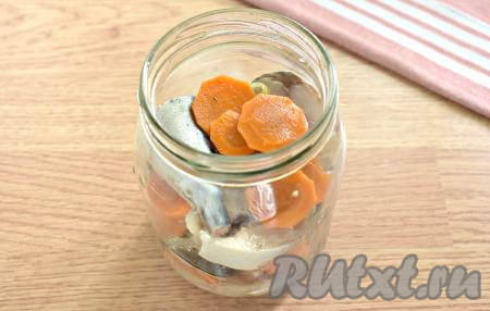 Кусочки скумбрии, а также лук и морковь из остывшего маринада выкладываем в банку (я использовала стеклянную банку объёмом 600 миллилитров).