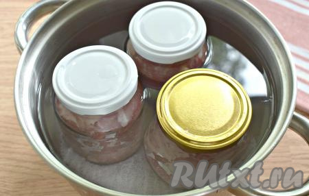 Банки накрываем крышками и немного прокручиваем крышку, но не до конца. Банки с мясом ставим в кастрюлю, дно которой нужно предварительно застелить полотенцем (или тканевой салфеткой). Заливаем в кастрюлю холодную воду, чтобы она была банкам «по плечики». Включаем сильный огонь, кастрюлю накрываем крышкой. Доводим воду до кипения. Убавляем немного огонь (вода должна кипеть, но не сильно). Варим так тушёнку из свинины в банках 2,5-3 часа. В течение варки я 2 раза подливала воду в кастрюлю, так как она выкипает.