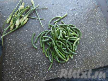 Чесночные стрелки помыть, удалить верхнюю семенную часть, затем сами стрелки нарезать на части, чтобы они были длиной 3-4 сантиметра. Очистить половину луковицы.