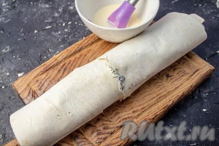 Начиная с узкого края, сверните лаваш в рулет. На противень, застеленный пергаментом, выложите рулет. Смажьте лаваш сверху оставшейся заливкой и поставьте минут на 20-25 в духовку, разогретую до 200 градусов.