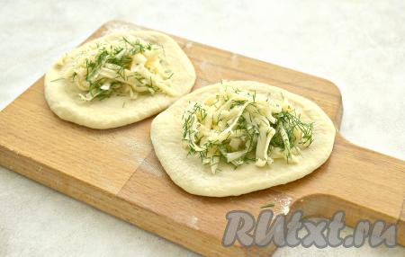 Сыр твёрдых сортов натираем на крупной тёрке и перемешиваем с нарезанным укропом. По столовой ложке получившейся смеси сыра и зелени выкладываем на середину каждой лепёшки.