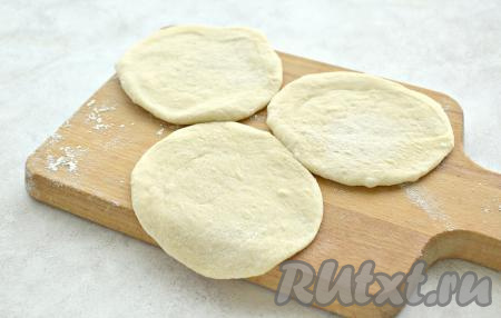 Поднявшееся дрожжевое тесто обминаем, делим на 12 кусочков. Кусочки теста прижимаем ладонью и на слегка присыпанной мукой поверхности раскатываем в лепёшки толщиной около 7 миллиметров.