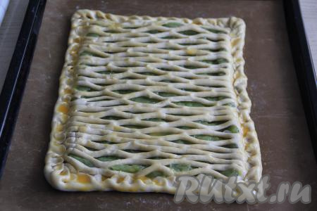 Выложить вторую часть слоёного теста поверх начинки из ревеня и хорошо скрепить края пирога. Яичный желток взбить вилкой, а затем смазать им верх пирога. Поставить противень с пирогом с ревенем в разогретую духовку. Выпекать минут 35 (слоёное тесто должно стать золотистого цвета) при температуре 180 градусов.