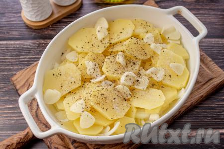 Картофель нарежьте на кружочки толщиной около 5 миллиметров и выложите его поверх лука. Поверх картошки разложите зубчики чеснока, нарезанные на тонкие пластины. Посолите и поперчите.