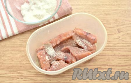 Кладём кусочек горбуши в контейнер. Аналогично полностью окунаем ещё несколько кусочков горбуши в масло и выкладываем в один слой на дно контейнера. Первый слой из горбуши посыпаем частью смеси соли и сахара.