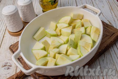 Кабачки вымойте. Если шкурка у кабачков тонкая и семечки мелкие, их можно не удалять. Нарежьте кабачки на крупные ломтики и выложите в глубокую форму для запекания.