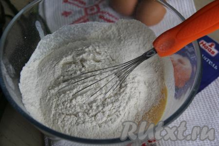 Всыпать просеянную муку и разрыхлитель. Перемешать тесто венчиком до однородности.