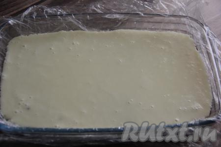 Полностью остывший бисквит разрезать на две части по горизонтали. В той же форме, в которой выпекали бисквит, будем формировать пирожное. Застелить форму пищевой плёнкой, края плёнки должны свисать с краёв формы. Выложить в форму одну часть коржа, влить сверху молочное суфле.