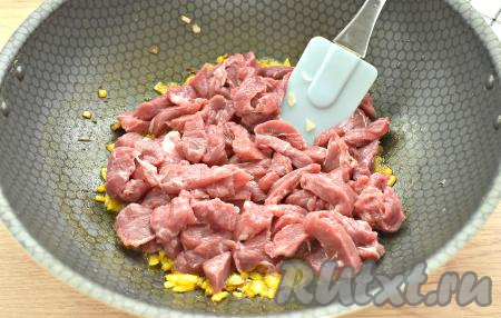 Затем в сковороду к луку с чесноком выкладываем кусочки говядины, делаем огонь чуть выше среднего. Обжариваем кусочки говядины минут 10, иногда перемешивая.