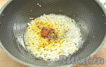 К обжаренному луку всыпаем молотую паприку и тмин, перемешиваем, обжариваем чеснок с луком, иногда помешивая, ещё 1 минуту.