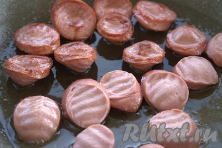 В сковороду влить растительное масло и выложить в один слой сосиски. Обжаривать сосиски с двух сторон до золотистого цвета на среднем огне (примерно, 2-3 минуты), затем переложить в отдельную тарелку и отставить в сторонку.