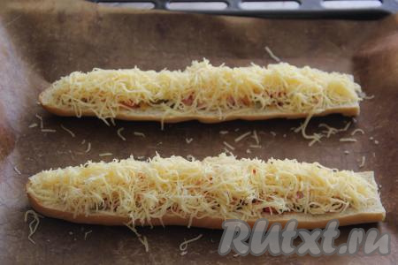 Переложить багеты с начинкой на противень, застеленный  ковриком для выпечки (или пергаментом). Сыр натереть на мелкой тёрке и посыпать его поверх начинки.